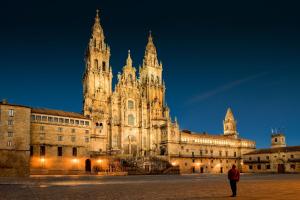 Ein Mann steht nachts vor einem großen Gebäude. in der Unterkunft Apartamento Lula in Santiago de Compostela