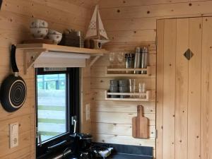 een keuken met houten wanden, een wastafel en een raam bij Little Lighthouse Texel in De Cocksdorp