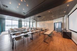 a conference room with tables and chairs and a screen at Ørland Kysthotell in Brekstad