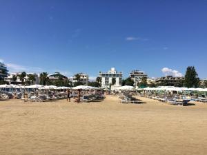 una spiaggia con sedie, ombrelloni e persone di Residence Dolce Vita a San Benedetto del Tronto