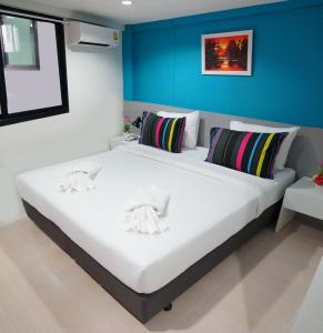 a large white bed in a room with a blue wall at Ma Non Nont Hotel & Apartment in Nonthaburi