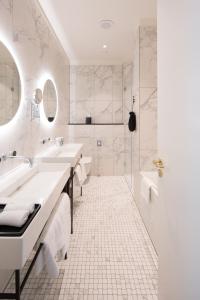 a white bathroom with two sinks and a shower at TORTUE Hamburg in Hamburg