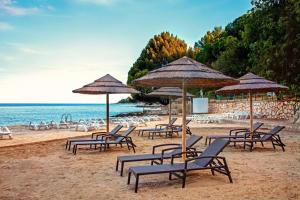 a group of chairs and umbrellas on a beach at Eva - Storia Parentina in Poreč