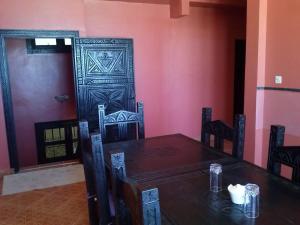 a dining room with a table and chairs and a door at Hôtel La Corniche in Akhfennirr