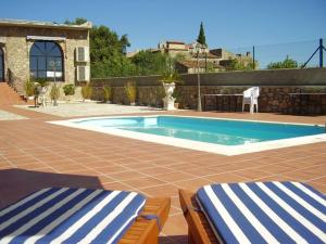 a swimming pool with two lounge chairs in front of a house at Hotel Rural El Convento in Valencia de Alcántara