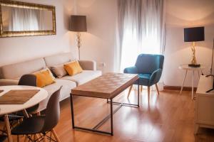 una sala de estar con un sofá, una mesa y sillas en Apartamentos Soho Boutique Plaza Mayor Caceres, en Cáceres
