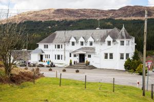 a large white building on the side of a road at Bridge of Orchy Hotel in Bridge of Orchy