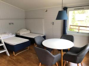 ein kleines Zimmer mit einem Tisch, Stühlen und einem Bett in der Unterkunft Elvegård Fjordcamp in Grov