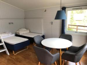 una piccola stanza con un tavolo, sedie e un letto di Elvegård Fjordcamp a Grov