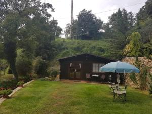 eine kleine Hütte mit einem Regenschirm im Gras in der Unterkunft Casa Horta in Aviá