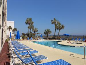 una piscina con tumbonas azules y una piscina en Ocean Club Resort Myrtle Beach a Ramada by Wyndham, en Myrtle Beach