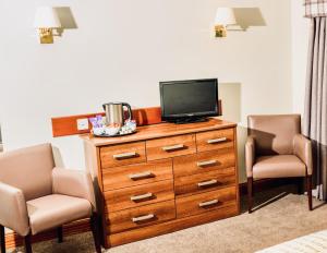 a room with a tv on a dresser with two chairs at Tyndrum Lodges in Tyndrum