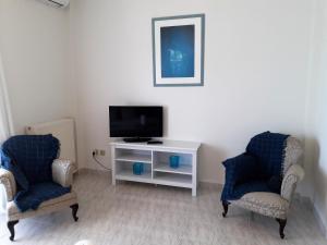 a living room with two chairs and a television at Kalos Gialos Sunrise Apartment in Porto Rafti