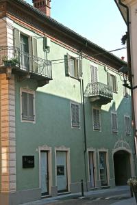 a green building with a balcony on a street at Appartamento Vandero in Alba
