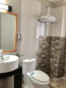 a bathroom with a white toilet and a sink at Khamsum Inn in Thimphu