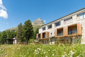 a building in a field with mountains in the background at Randolins Familienresort in St. Moritz