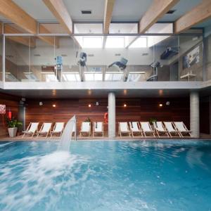 a large swimming pool with a fountain in a building at Apartament w Hotelu Sand in Kołobrzeg