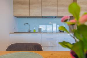 a kitchen with white cabinets and a wooden table at Apartamenty Laguna Przy Latarni in Darlowko