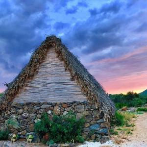 un edificio con un tetto in erba in cima a un muro di pietra di Ovile Juanne Loddo a Orosei