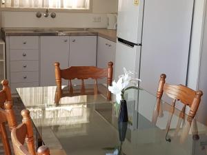 a kitchen with a table, chairs and a refrigerator at Kipparing Village Motel in Redcliffe