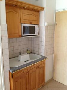 uma pequena cozinha com um lavatório e um micro-ondas em Kosztolányi Apartmanház em Balatonfüred