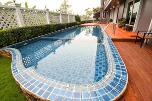 a swimming pool with blue tiles on a deck at Convenient Grand Hotel in Lat Krabang