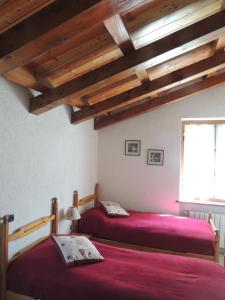two beds in a room with wooden ceilings at Ico's Lodge in Sauze dʼOulx