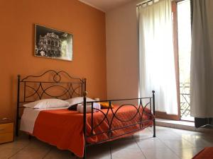 1 dormitorio con 1 cama con paredes de color naranja y ventana en Platamone Rooms, en Catania