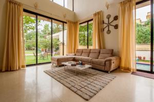 a living room with a couch and a table at StayVista's Greenwoods Villa 1 - City-Center Villa with Private Pool, Terrace, Lift & Carrom Board in Lonavala +16 photos