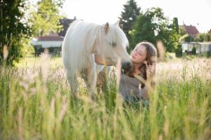 a woman sitting in a field with a white horse at Ferienwohnung Spie in Sarkwitz