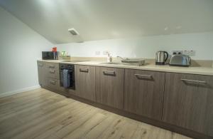 una cocina con armarios de madera y fregadero en Meadow view apartment, en Carncastle
