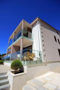 a large white building with a balcony and a tree at Vila Orada in Molat