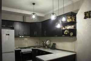 Una cocina con gabinetes negros y un refrigerador blanco. en Apartment Galaxy Didi Dighomi, en Tiflis