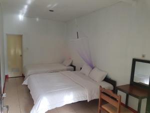 1 dormitorio con 2 camas y TV. en Antoneri Lodge, en Kelimutu