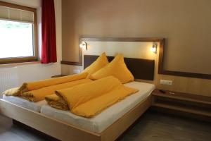 um quarto com uma cama com cobertores e almofadas amarelos em Haus Alpina & Landhaus Schöpf em Längenfeld