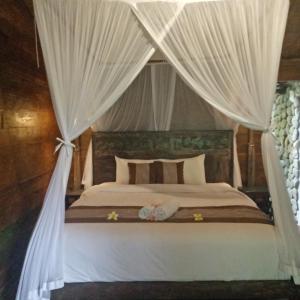 Un dormitorio con una cama con dosel y cortinas blancas. en Melati Bali Homestay, en Canggu