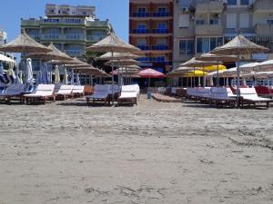 un grupo de sillas y sombrillas en una playa en Hotel 3 Vellezerit, en Durrës