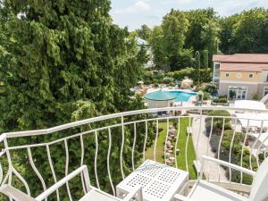a balcony with white chairs and a swimming pool at Travel Charme Strandidyll Heringsdorf in Heringsdorf