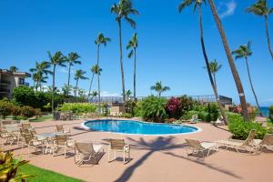 a pool with chairs and palm trees in a resort at Hale Ono Loa 406 in Honokowai