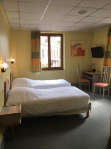 a bedroom with a bed and a desk and a window at Hostellerie d'Alsace in Cernay