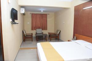 a hotel room with a bed and chairs and a television at Hotel Surya Residency Majestic in Bengaluru
