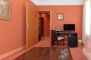 a living room with orange walls and a desk with a computer at Hotel Soho Boutique Jerez in Jerez de la Frontera