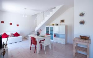 uma sala de estar branca com uma mesa branca e cadeiras vermelhas em Casa Mari em Marina di Ragusa