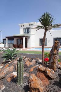 een huis met een palmboom en wat rotsen bij Hipoclub Villas, Aguamarina 2 in Playa Blanca