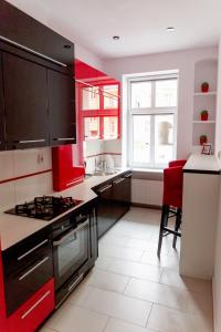 a kitchen with red cabinets and a stove top oven at Apartament Różany in Gorzów Wielkopolski