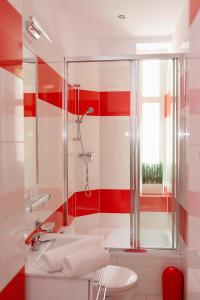 a red and white bathroom with a shower and a sink at Apartament Różany in Gorzów Wielkopolski