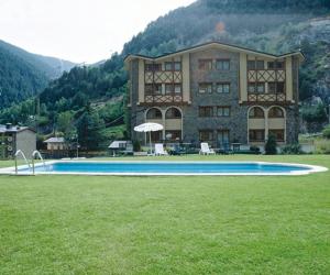 a large building with a swimming pool in the grass at Hotel Xalet Verdú in Arinsal