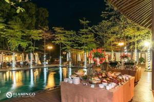 una mesa con comida junto a una piscina por la noche en Flamingo Villa Happy BT, en Ngọc Quang