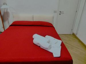 un letto rosso con due asciugamani bianchi sopra di A Casetta a Tivoli
