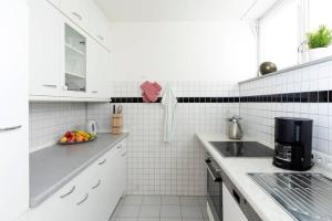 a white tiled kitchen with a bowl of fruit on the counter at Abendrot Appartement in Ober-Hambach